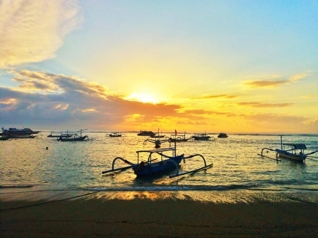 Traditional jukung boats resting on the sand during a calm morning, symbolizing the best time to visit Sanur for cultural scenery.